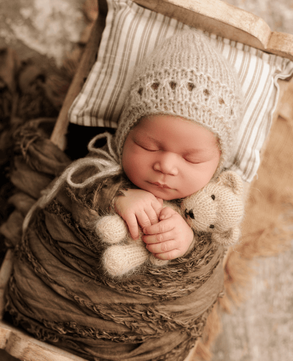 Newborn boy in a photography studio in Grants Pass, Oregon holding a teddy bear.