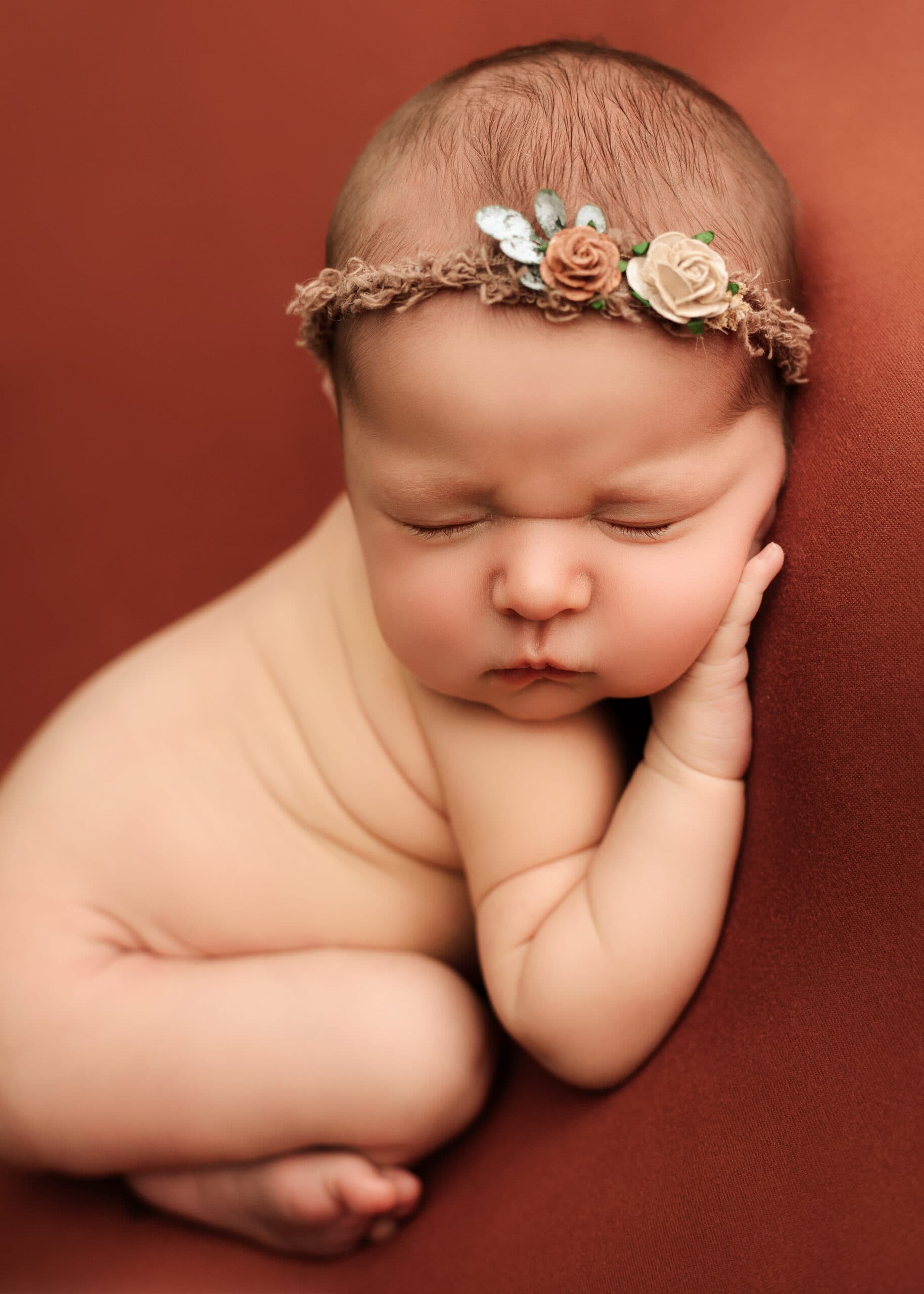 Newborn girl posed in Grants Pass, Oregon studio with flower headband.