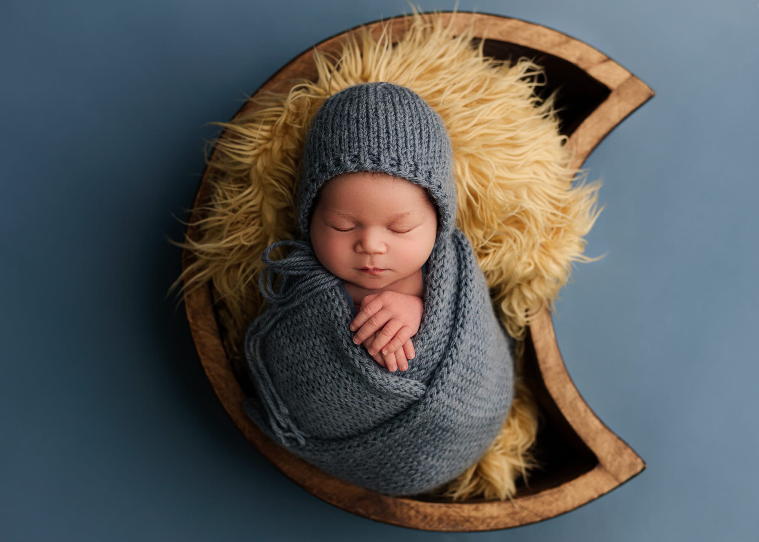 Medford, Oregon Newborn boy in a photographers studio with blue backdrop.