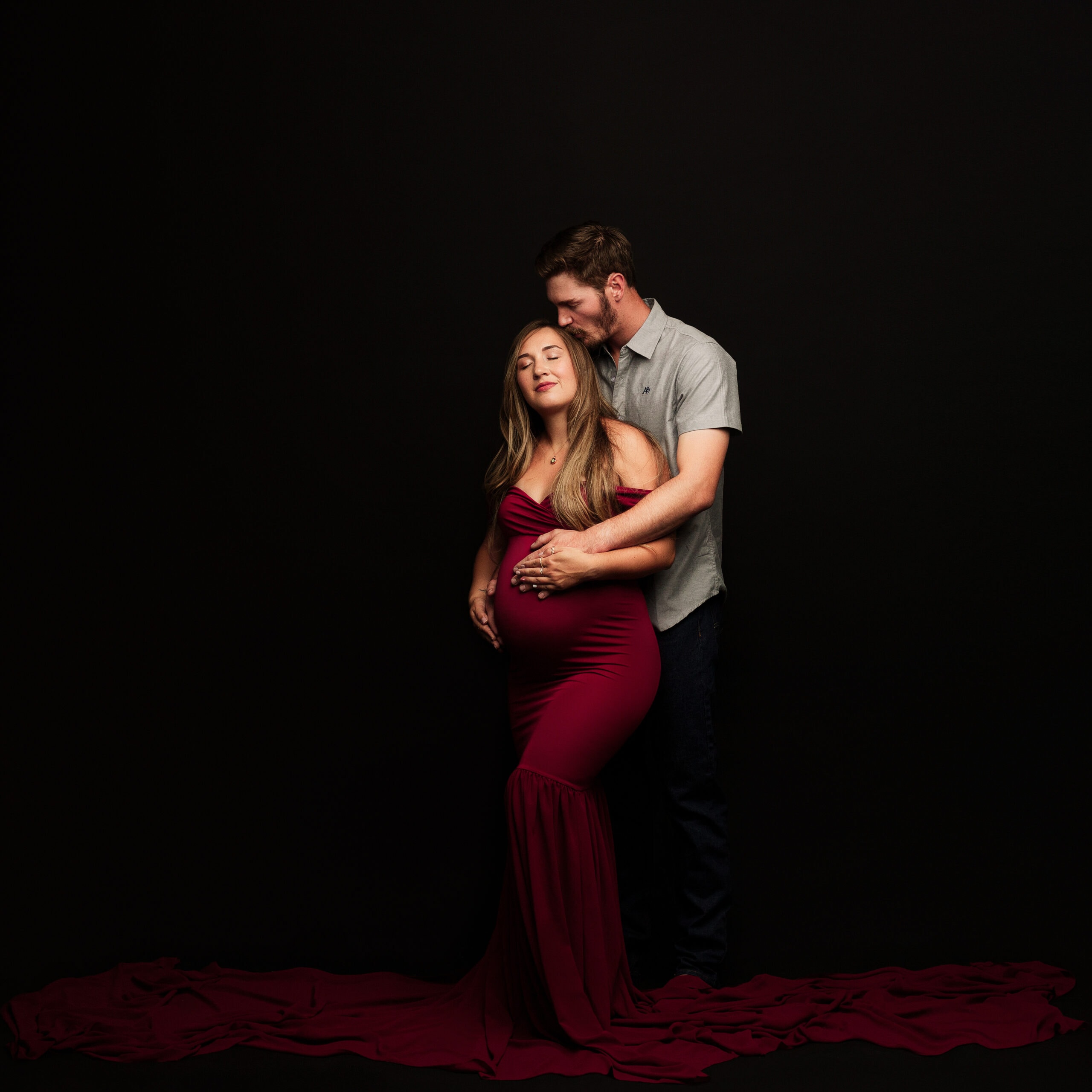 In studio maternity photography session of husband and wife.