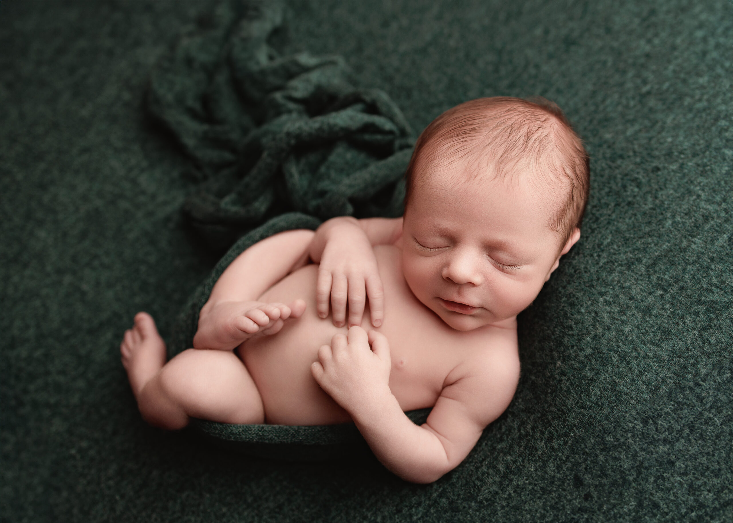 Infant posed on green fabric drop for infants photos in Grants Pass