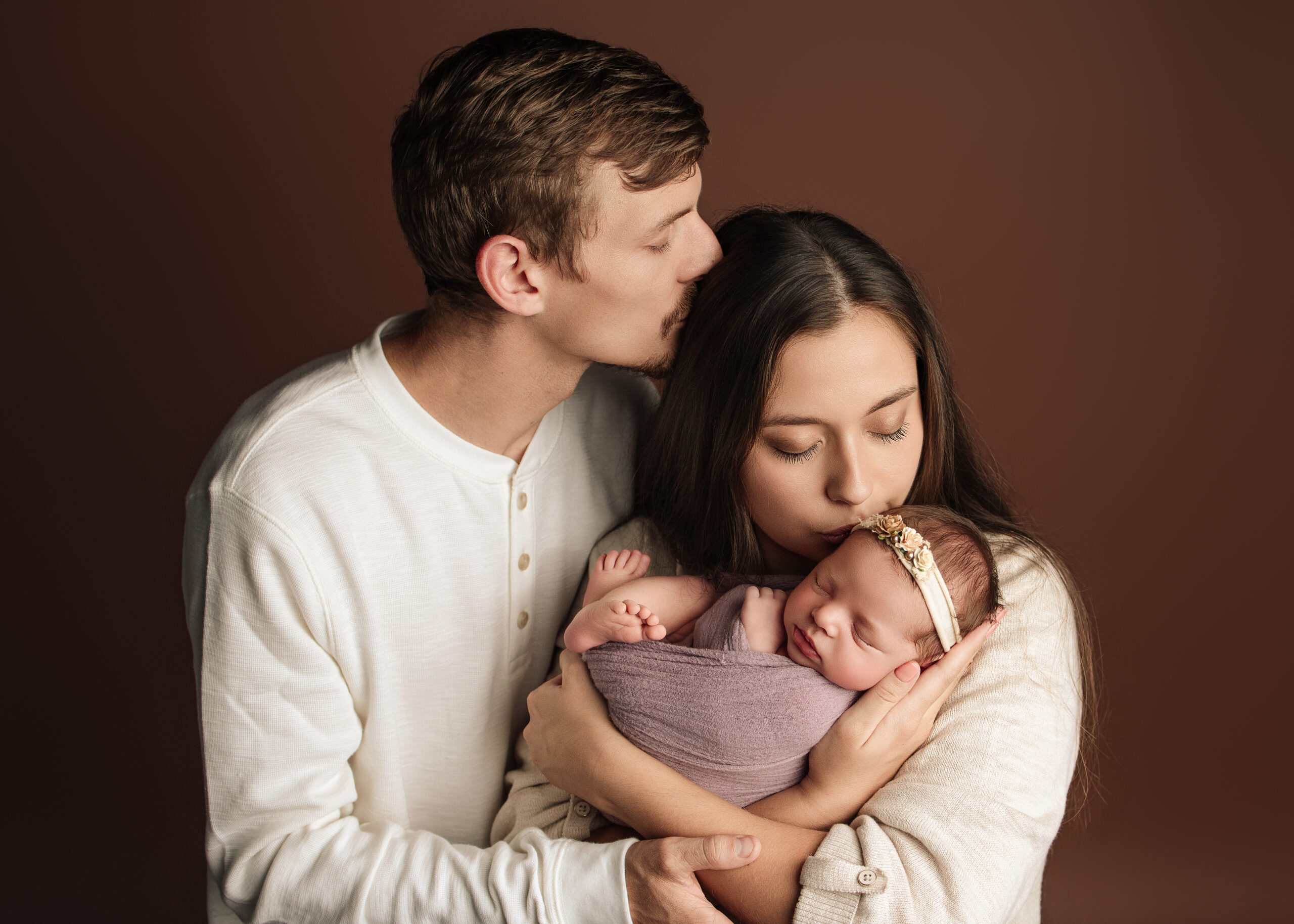 A family of three taking a photo for a baby photographer for first time parents Grants Pass